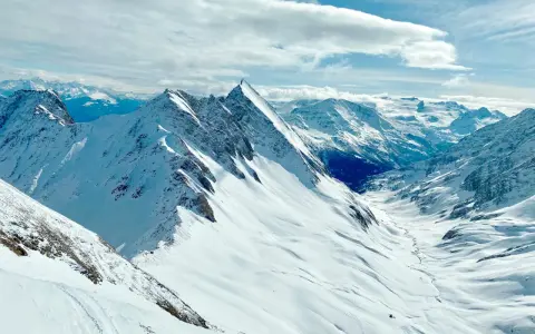 Vette innevate e un cielo azzurro con nuvole soffici, un panorama mozzafiato per chi cerca cosa vedere a Courmayeur.