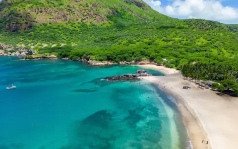Spiaggia tropicale con acque turchesi e montagne verdi. Un luogo perfetto per scoprire cosa vedere a Capo Verde, tra relax e natura.