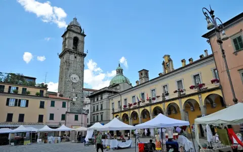 Mercato in piazza a Pontremoli, con la torre civica e il palazzo del Comune. Ecco cosa vedere a Pontremoli: un'atmosfera vivace.