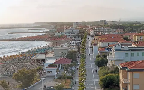 Vista aerea del lungomare di Marina di Cecina con spiaggia attrezzata, mare calmo e case con tetti rossi.