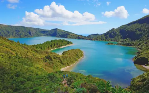 Lago blu circondato da colline verdi lussureggianti, con piccole isole e una spiaggia sabbiosa. Perfetto per capire quando andare alle Azzorre.