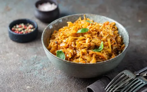 Cavolo stufato, un classico da provare per scoprire cosa mangiare a Varsavia. Servito in una ciotola con erbe fresche, pepe e sale.