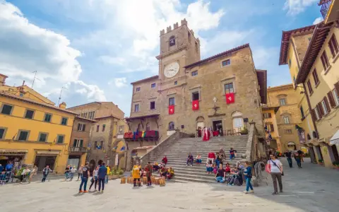 Piazza del Popolo a Cortona, dove si trova questo antico palazzo con torre dell'orologio, animata da turisti e figuranti in costume.