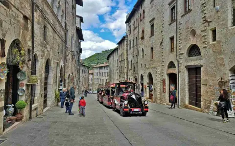 Treno turistico attraversa una strada acciottolata di Gubbio, un'idea per cosa vedere a Gubbio in un giorno.