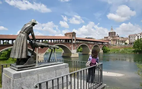 Pavia cosa vedere in un giorno: il Ponte Coperto con la statua della lavandaia e la cupola del Duomo sullo sfondo.