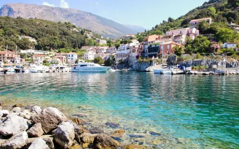 Un borgo colorato su una collina, con barche e yacht in un mare cristallino. Un esempio di posti belli da visitare in Italia a poco prezzo.