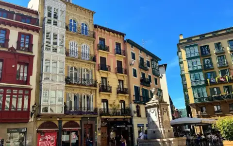 Edifici colorati con balconi in ferro battuto e una fontana in una piazza. Perfetto per scoprire cosa vedere a Bilbao in 3 giorni.