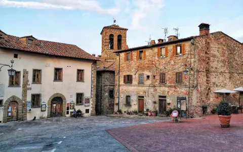 Piazza di un borgo toscano, ideale tra i borghi da visitare in 2 giorni. Edifici in pietra e mattoni, campanile e scorci suggestivi.