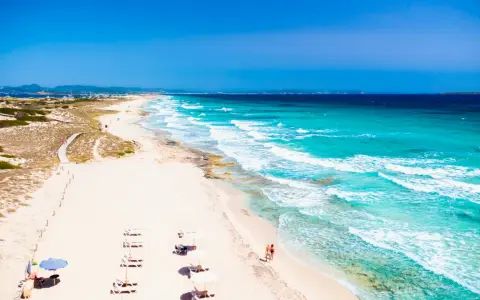 Spiaggia da sogno in Spagna dove andare al mare: sabbia bianca, acque turchesi e un sentiero tra le dune.