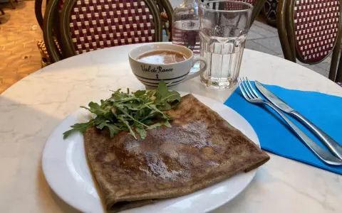 Crepe salata con rucola, una tazza di caffè e un bicchiere d'acqua, un assaggio dei piatti tipici parigini.