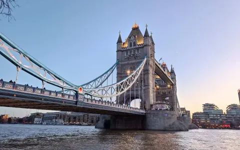La Tower Bridge illuminata, un'icona per chi ama viaggiare a Londra, si specchia sul Tamigi al tramonto.