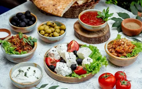 Un banchetto di piatti tipici grecia: feta fresca, olive nere e verdi, salsa di pomodoro, melanzane e pane pita.