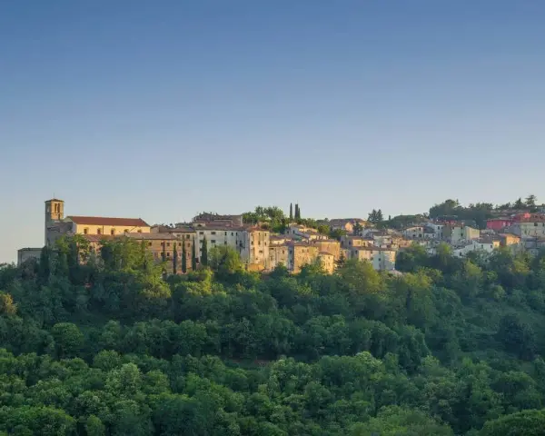 Borgo collinare con chiesa e case in pietra, immerso nel verde. Un luogo incantevole dove scansano cosa vedere, tra storia e natura.