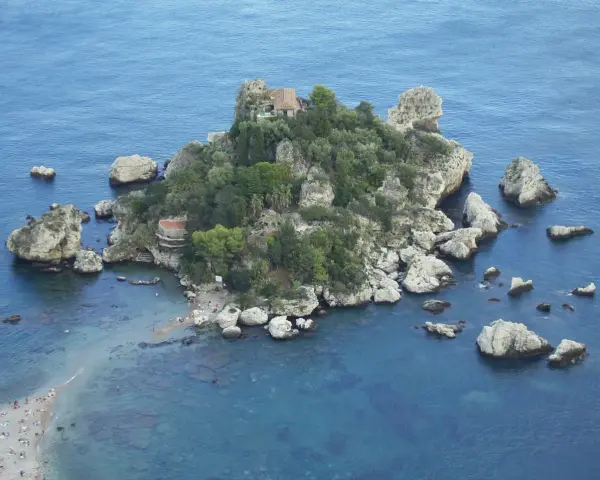Isola Bella, una gemma tra le spiagge Sicilia orientale, con rocce e vegetazione lussureggiante che si tuffano nel mare cristallino.