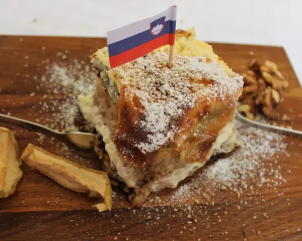 Fetta di torta con bandiera slovena, noci e mele essiccate, un assaggio dei piatti tipici sloveni.