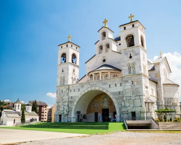 La Cattedrale della Resurrezione di Cristo a Podgorica, cosa vedere: imponente architettura ortodossa con torri campanarie e croci dorate sotto un cielo azzurro.