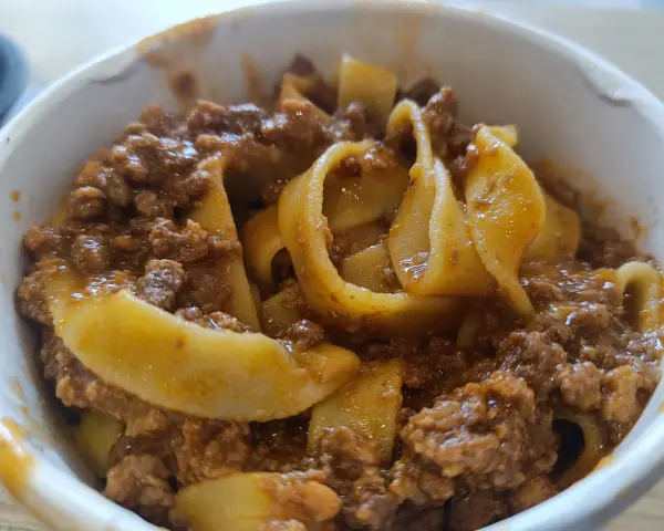 Tagliatelle al ragù, un classico su cosa mangiare a Bologna. Pasta fresca con sugo di carne saporito in una ciotola.