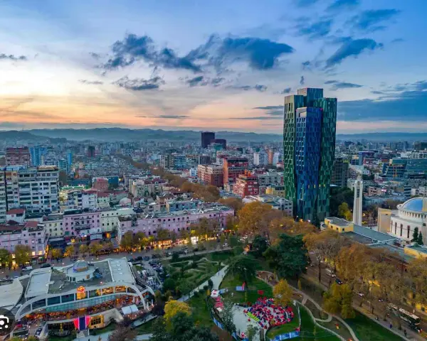 Panoramica di Tirana al tramonto, con grattacieli colorati e un parco. Ideale per scoprire cosa vedere a Tirana in 3 giorni.