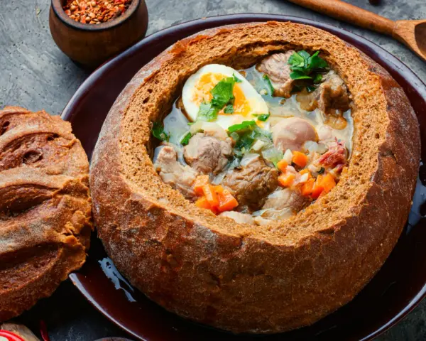 Zuppa polacca servita in una pagnotta scavata, un'ottima idea per cosa mangiare a Cracovia. Carne, uova e verdure in un pane croccante.