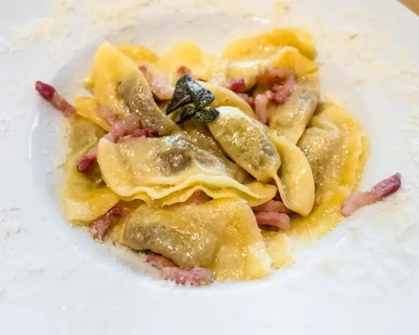 Ravioli ripieni, conditi con pancetta e salvia, un classico dei piatti tipici bergamaschi, spolverati di formaggio grattugiato.