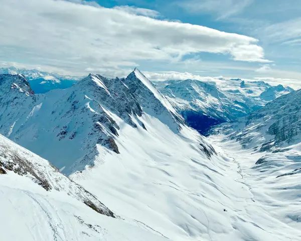 Vette innevate e un cielo azzurro con nuvole soffici, un panorama mozzafiato per chi cerca cosa vedere a Courmayeur.
