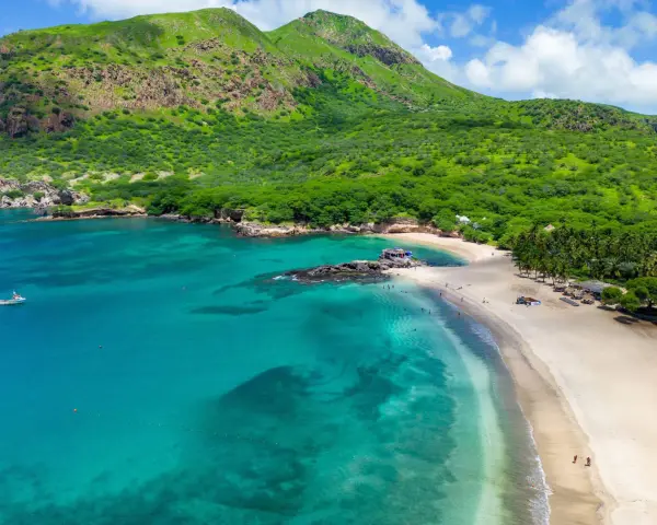 Spiaggia tropicale con acque turchesi e montagne verdi. Un luogo perfetto per scoprire cosa vedere a Capo Verde, tra relax e natura.