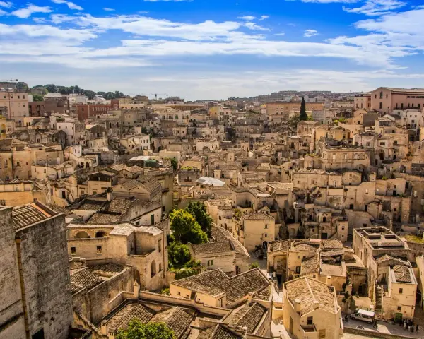 Panoramica di Matera, la città più antica del mondo, con i suoi Sassi scavati nella roccia e le case in pietra sotto un cielo azzurro.