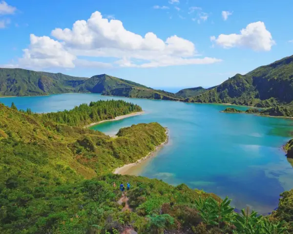 Lago blu circondato da colline verdi lussureggianti, con piccole isole e una spiaggia sabbiosa. Perfetto per capire quando andare alle Azzorre.