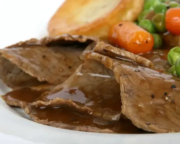 Fette di arrosto con sugo, piselli, carote e patate arrosto, un classico tra i piatti tipici del Regno Unito.