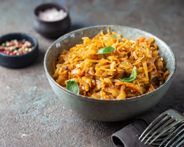 Cavolo stufato, un classico da provare per scoprire cosa mangiare a Varsavia. Servito in una ciotola con erbe fresche, pepe e sale.
