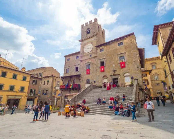 Piazza del Popolo a Cortona, dove si trova questo antico palazzo con torre dell'orologio, animata da turisti e figuranti in costume.