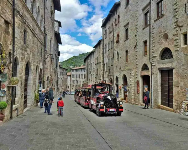 Treno turistico attraversa una strada acciottolata di Gubbio, un'idea per cosa vedere a Gubbio in un giorno.