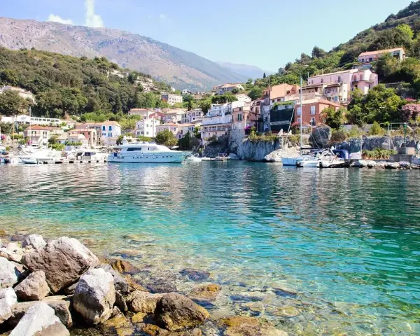 Un borgo colorato su una collina, con barche e yacht in un mare cristallino. Un esempio di posti belli da visitare in Italia a poco prezzo.