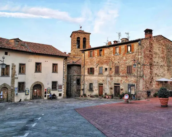 Piazza di un borgo toscano, ideale tra i borghi da visitare in 2 giorni. Edifici in pietra e mattoni, campanile e scorci suggestivi.