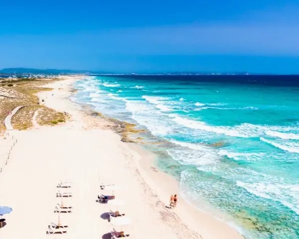 Spiaggia da sogno in Spagna dove andare al mare: sabbia bianca, acque turchesi e un sentiero tra le dune.