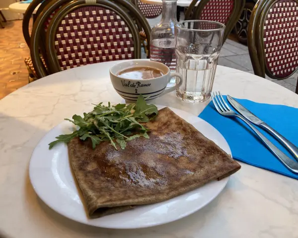 Crepe salata con rucola, una tazza di caffè e un bicchiere d'acqua, un assaggio dei piatti tipici parigini.