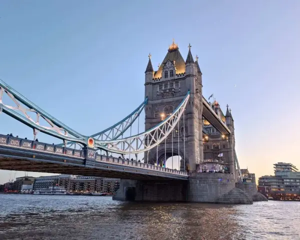 La Tower Bridge illuminata, un'icona per chi ama viaggiare a Londra, si specchia sul Tamigi al tramonto.