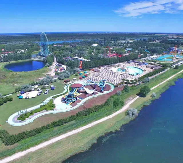 Vista aerea di Mirabilandia, un parco divertimenti con acquascivoli, piscine e una ruota panoramica, situato vicino a un lago.