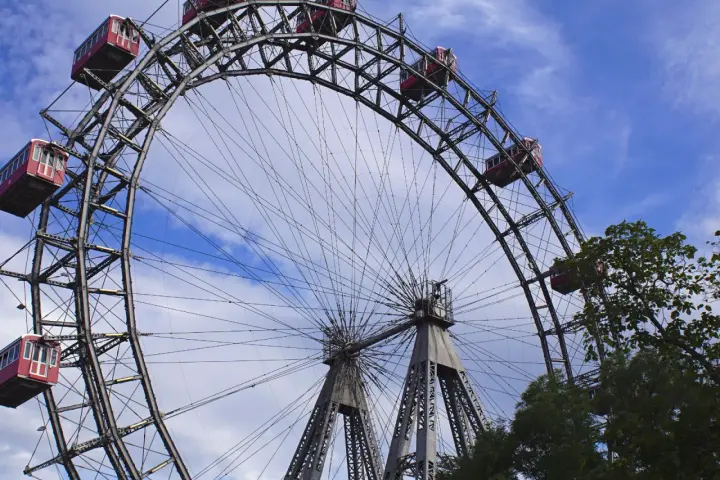 La Ruota Panoramica di Vienna, un'icona per chi cerca cosa vedere a Vienna in 1 giorno, con le sue cabine rosse sotto un cielo azzurro.