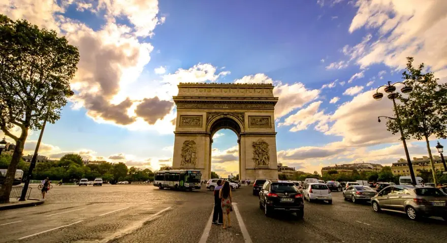 Arco di Trionfo, un'icona di cosa vedere a Parigi, con traffico e nuvole al tramonto.