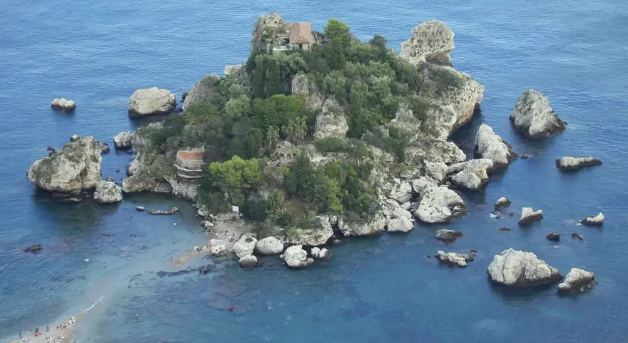 Isola Bella, una gemma tra le spiagge Sicilia orientale, con rocce e vegetazione lussureggiante che si tuffano nel mare cristallino.