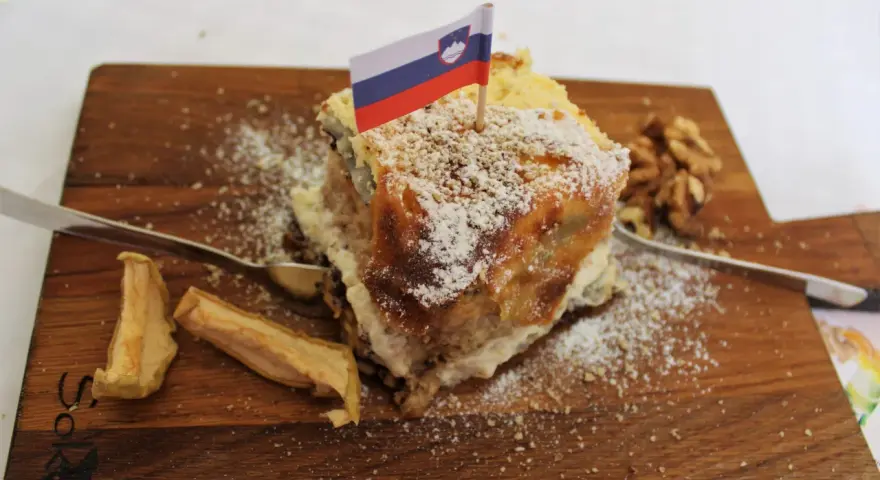 Fetta di torta con bandiera slovena, noci e mele essiccate, un assaggio dei piatti tipici sloveni.