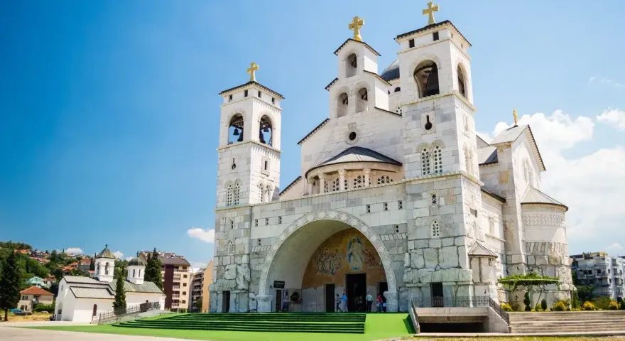 La Cattedrale della Resurrezione di Cristo a Podgorica, cosa vedere: imponente architettura ortodossa con torri campanarie e croci dorate sotto un cielo azzurro.