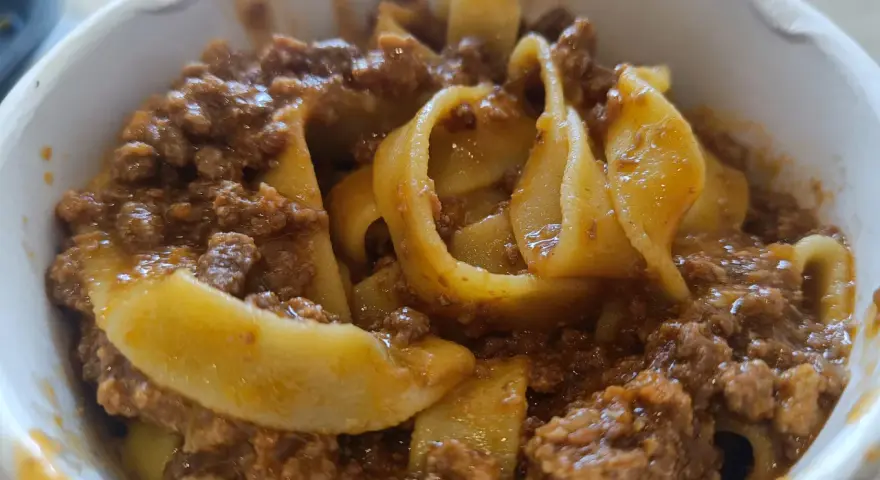 Tagliatelle al ragù, un classico su cosa mangiare a Bologna. Pasta fresca con sugo di carne saporito in una ciotola.