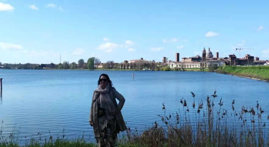 Donna con sciarpa e cappotto ammira il panorama di Mantova, un luogo incantevole da esplorare.