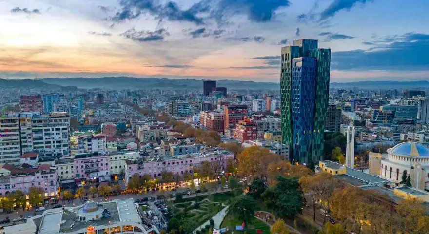 Panoramica di Tirana al tramonto, con grattacieli colorati e un parco. Ideale per scoprire cosa vedere a Tirana in 3 giorni.