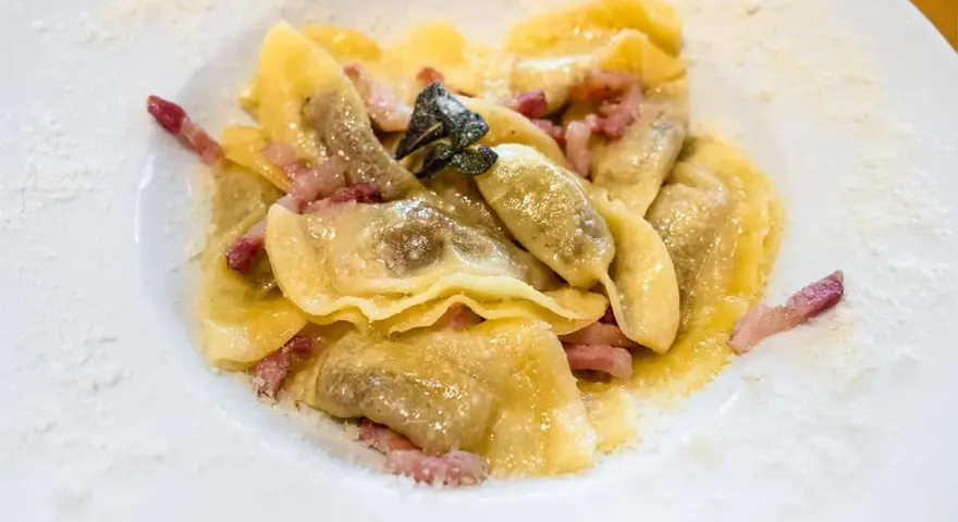 Ravioli ripieni, conditi con pancetta e salvia, un classico dei piatti tipici bergamaschi, spolverati di formaggio grattugiato.