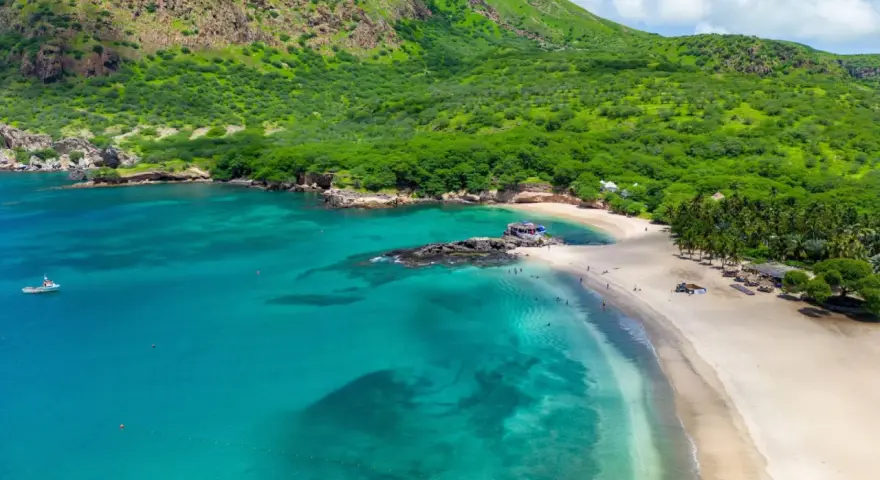 Spiaggia tropicale con acque turchesi e montagne verdi. Un luogo perfetto per scoprire cosa vedere a Capo Verde, tra relax e natura.