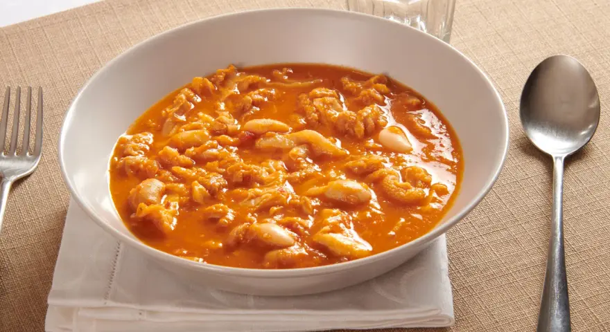 Piatto tipico pisano: trippa alla pisana in un bianco piatto, servita con forchetta e cucchiaio.