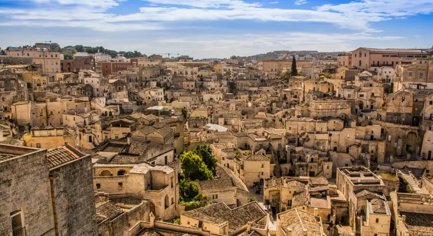 Panoramica di Matera, la città più antica del mondo, con i suoi Sassi scavati nella roccia e le case in pietra sotto un cielo azzurro.